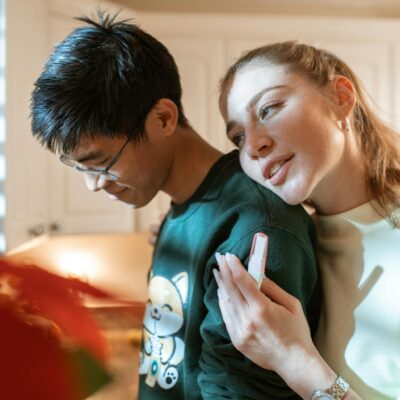Woman in White and Black Shirt Holding Smartphone Beside Man in Green Crew Neck Shirt