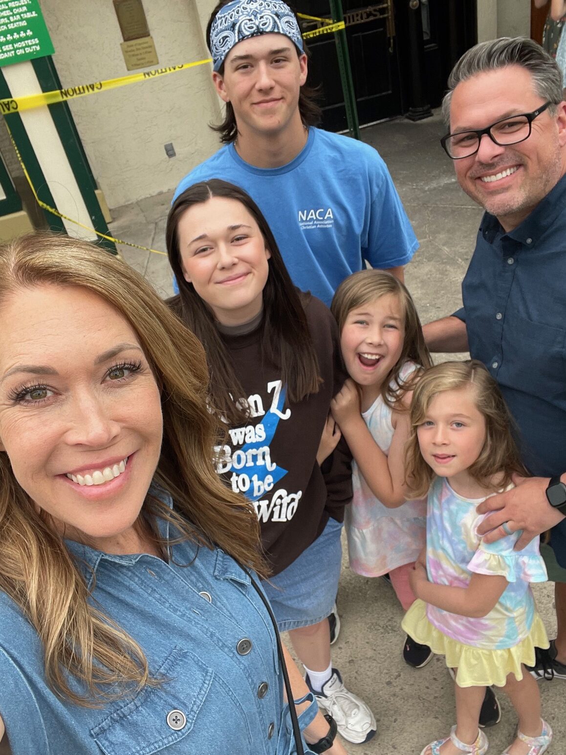 family of six taking selfie in front of Jade East Towers in Destin Florida