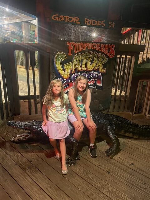 two kids sitting on a bench that looks like an alligator at fudpuckers in destin, florida