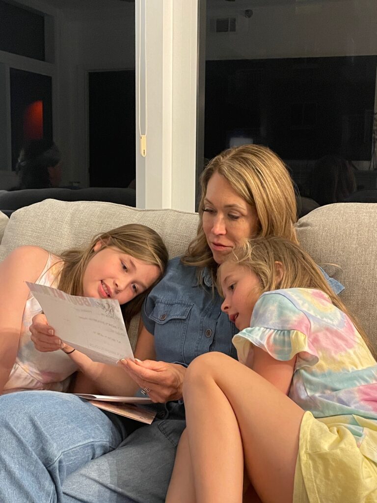 mom with two young daughters sitting on the couch reading her mothers day card in destin florida