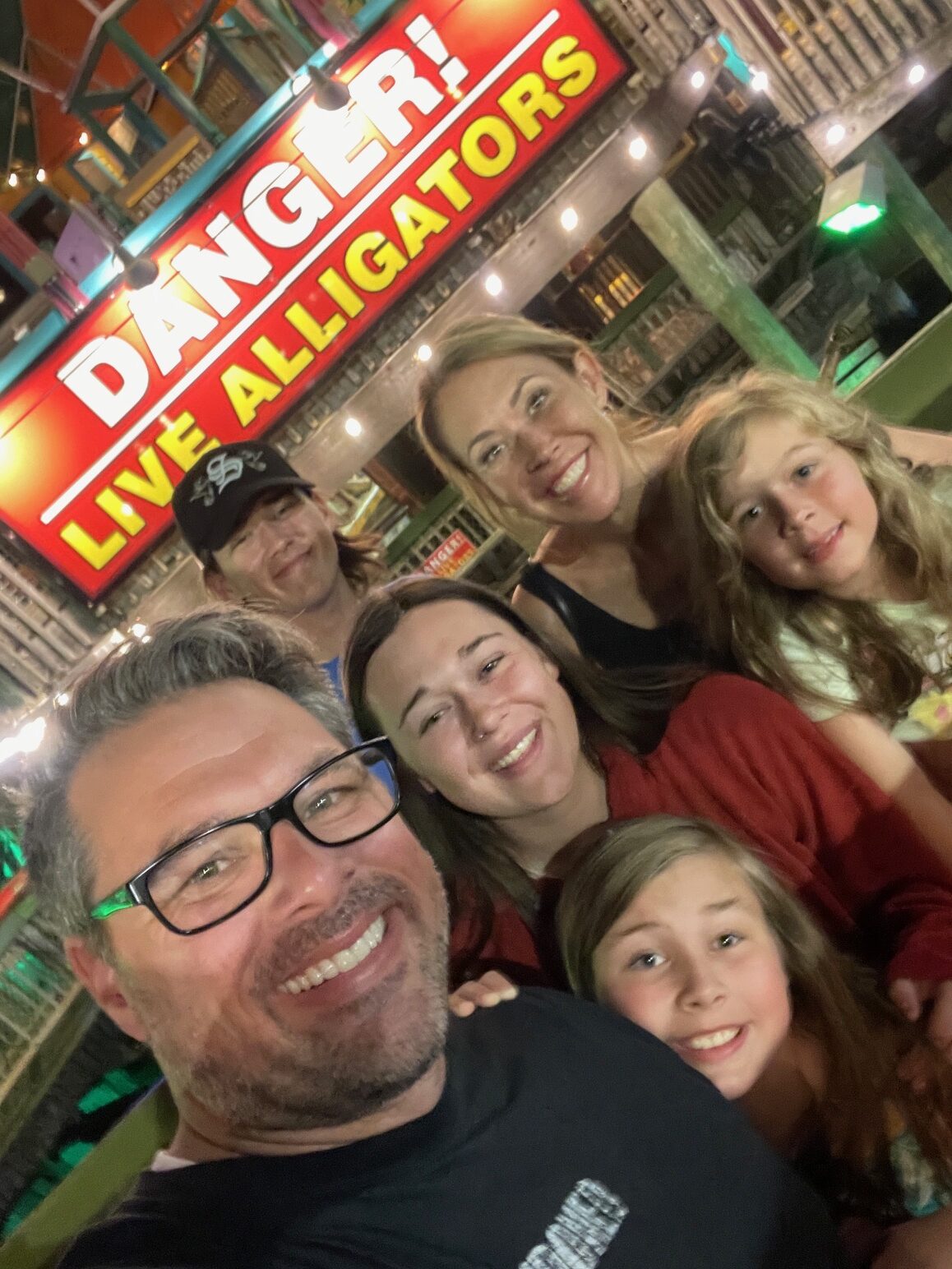 family of six taking a selfie in front of a danger sign at fudpucker's in destin, florida