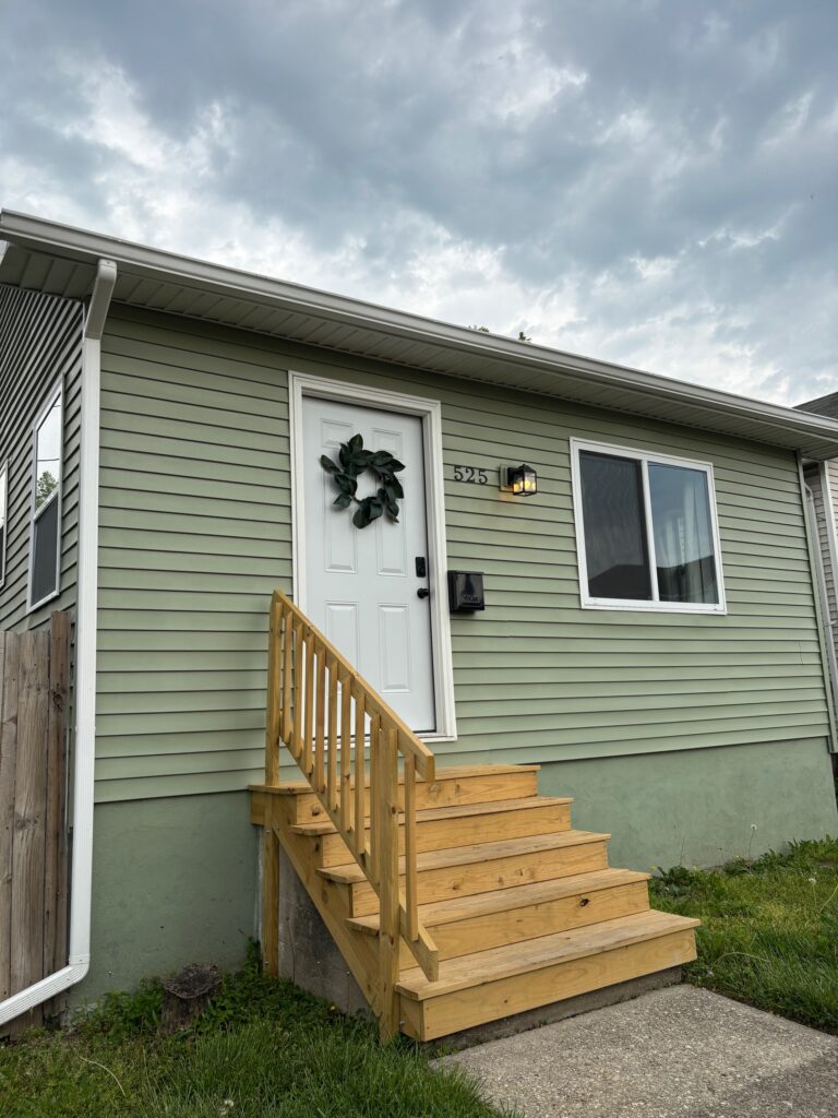 Exterior photo of green bungalow style home reminding us of why we choose short term rentals over hotels
