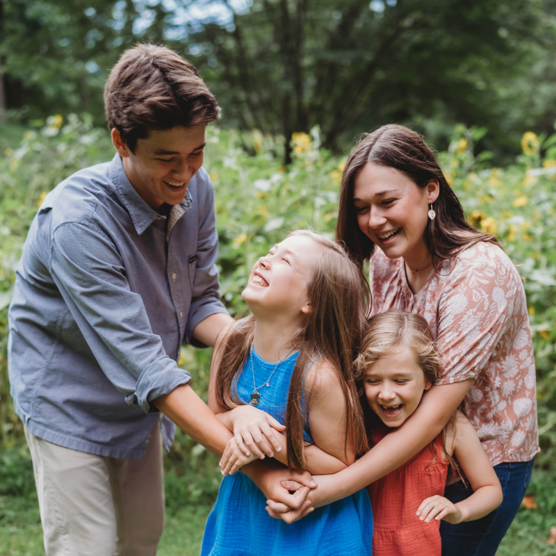 family of 4 siblings holding each other, smiling/laughing for a lifestyle photo