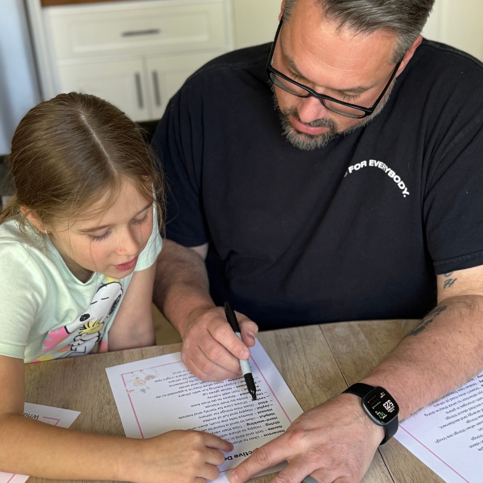 Father and daughter sitting at a table, filling out a "What Do You See in Me?" character worksheet together.
