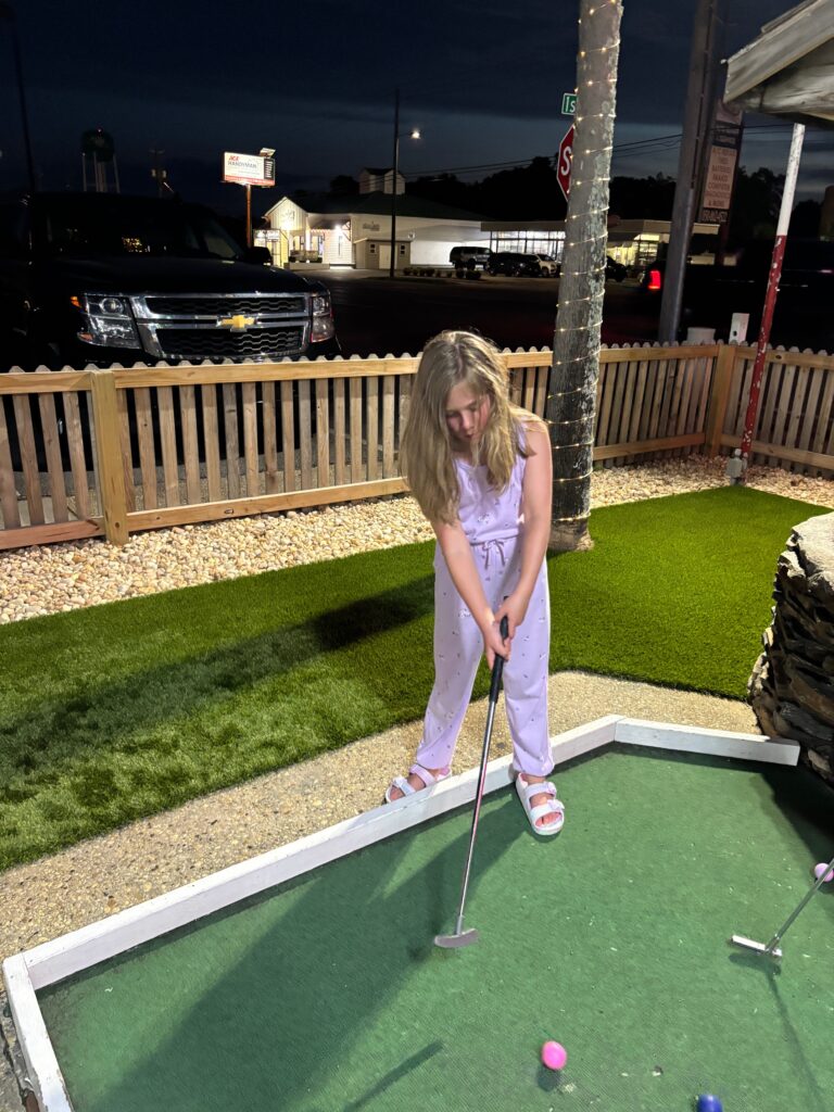 young girl playing mini golf