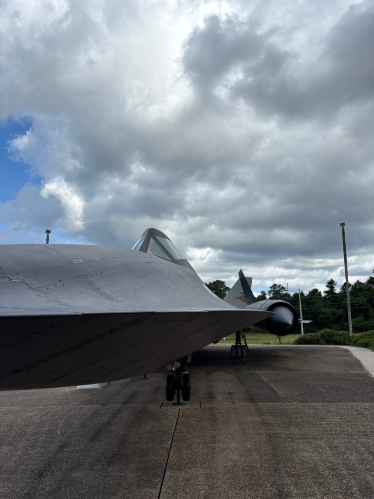 Black military airplane with blue cloudy sky behind it